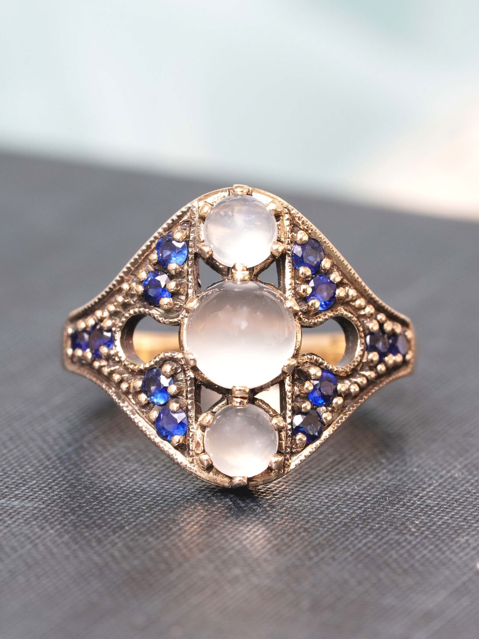 9K Yellow Gold Natural Moon stone and Blue Sapphire Vintage Style Three stone Ring: CHARACTERISTICSOrigin: ThailandMetal: Solid 9K Yellow GoldRing Size: US 7Total Gemstones Weight: 2.37 carat. (approx.)Total Gram Weight: 5.07 g. (approx.)*Pictures have been enlarged to show details*P