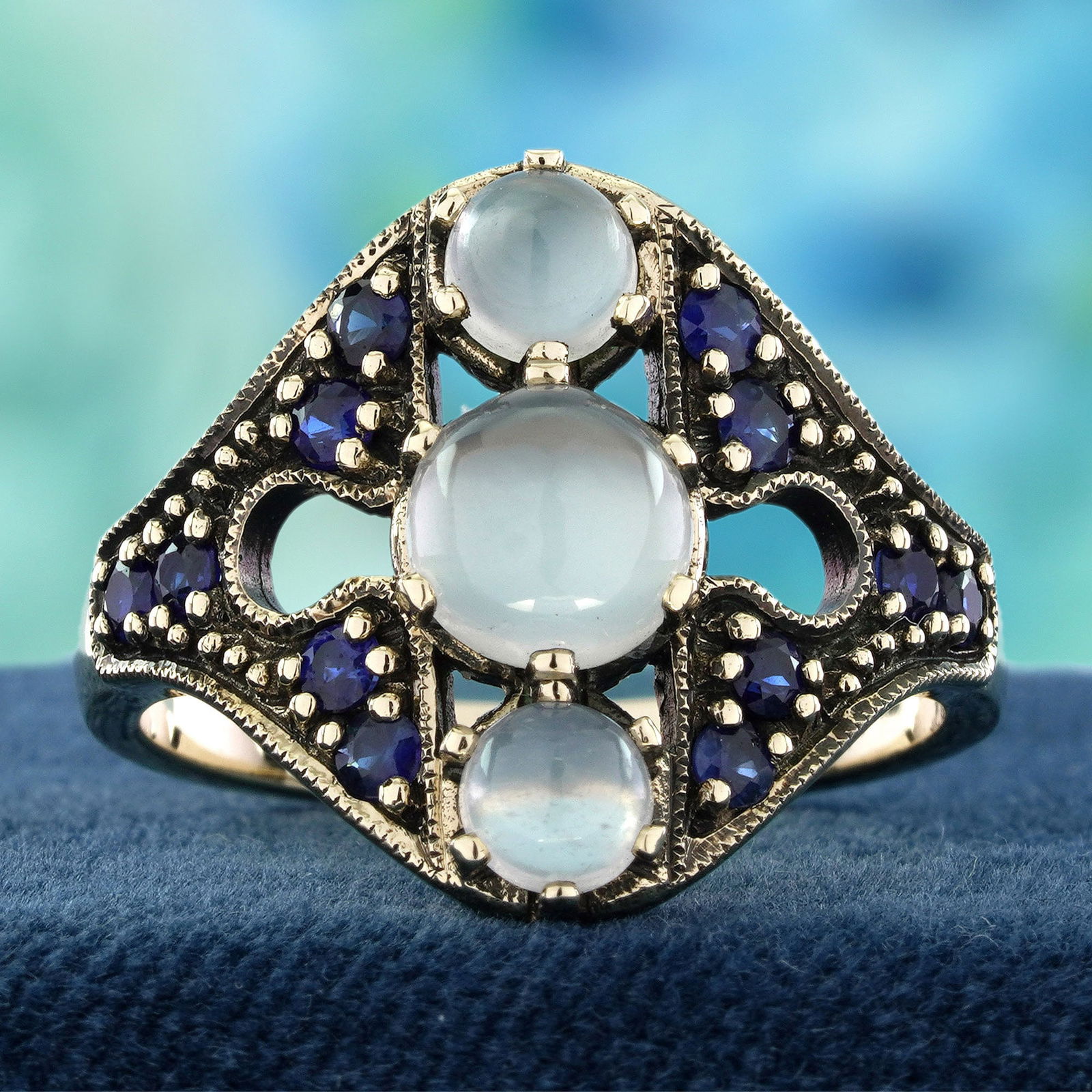 9K Yellow Gold Natural Moon stone and Blue Sapphire Vintage Style Three stone Ring: CHARACTERISTICSOrigin: ThailandMetal: Solid 9K Yellow GoldRing Size: US 7Total Gemstones Weight: 2.37 carat. (approx.)Total Gram Weight: 5.07 g. (approx.)*Pictures have been enlarged to show details*P