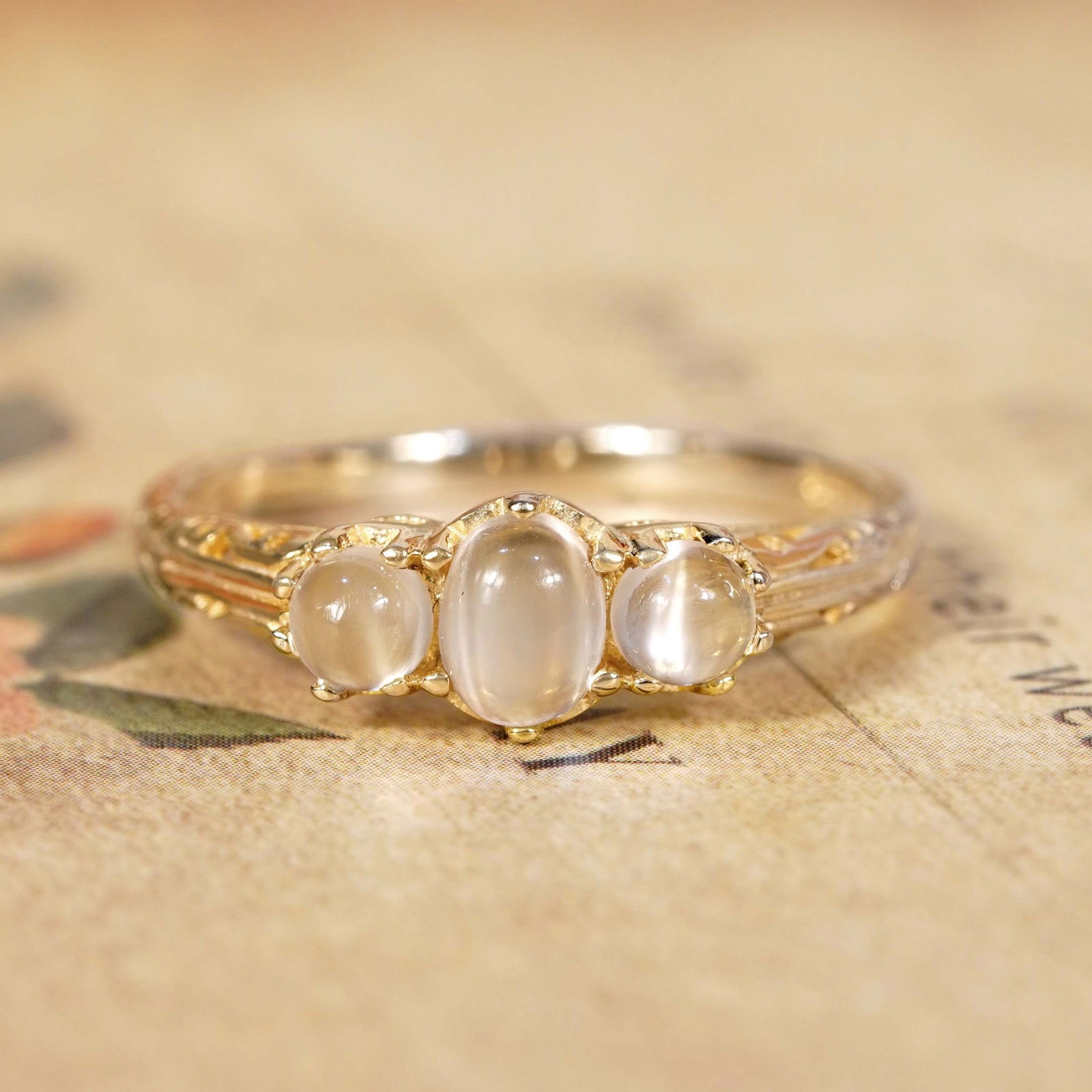 9K Yellow Gold Natural Moonstone Vintage Style Three Stone Ring: CHARACTERISTICSOrigin: ThailandMetal: Solid 9K Rose GoldRing Size: US 7Total Gemstones Weight: 0.98 carat. (approx.)Total Gram Weight: 1.62 g. (approx.)*Pictures have been enlarged to show details*GEM