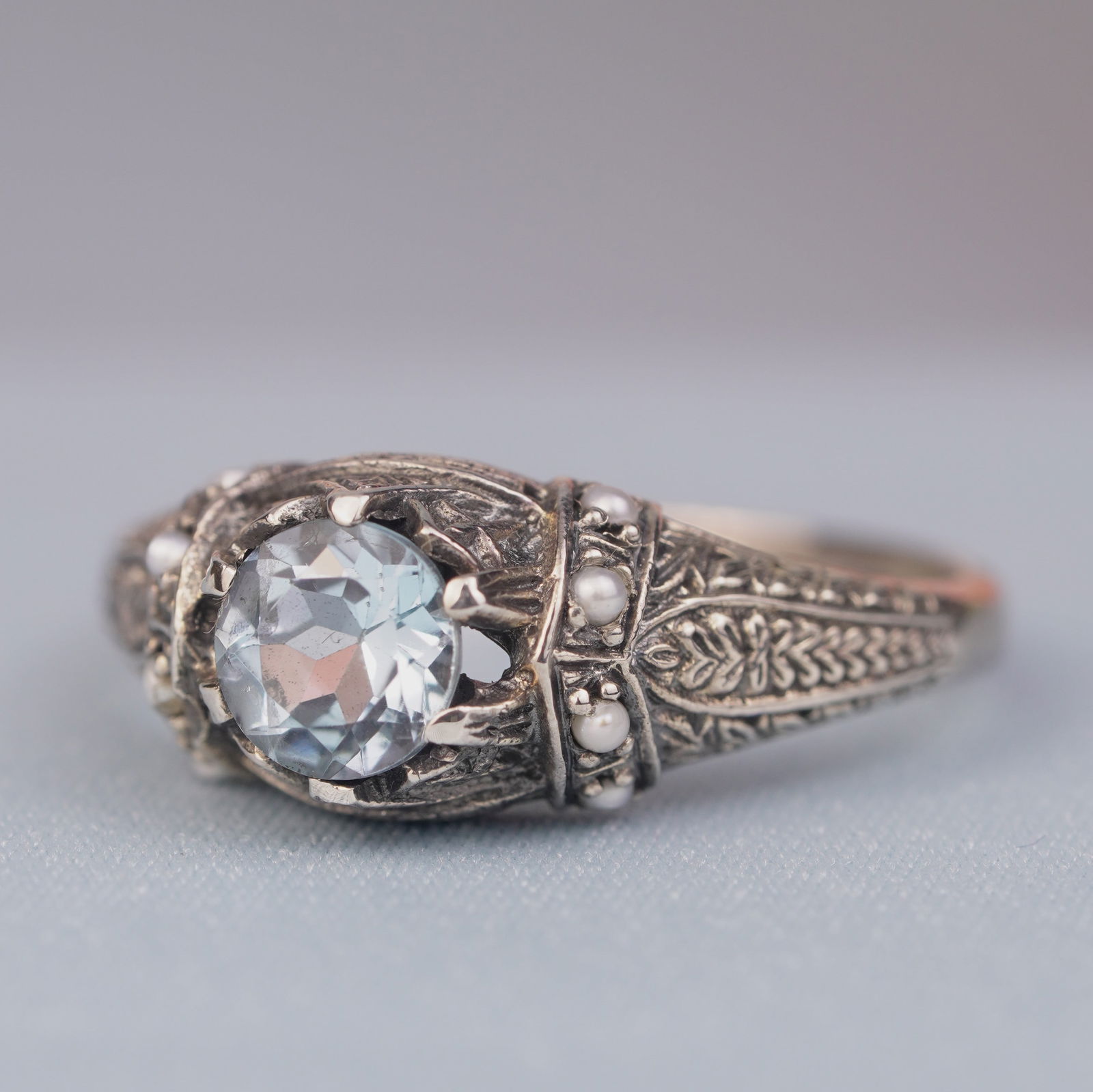 Silver925 Natural Blue Topaz Pearl Vintage Filigree Ring: CHARACTERISTICSStatus: In stockOrigin: ThailandMetal: Silver 925Ring Size: US 9Total Gemstones Weight: 1.18 carat. (approx.)Total Gram Weight: 3.04 g. (approx.)*Pictures have been enlarged to show det