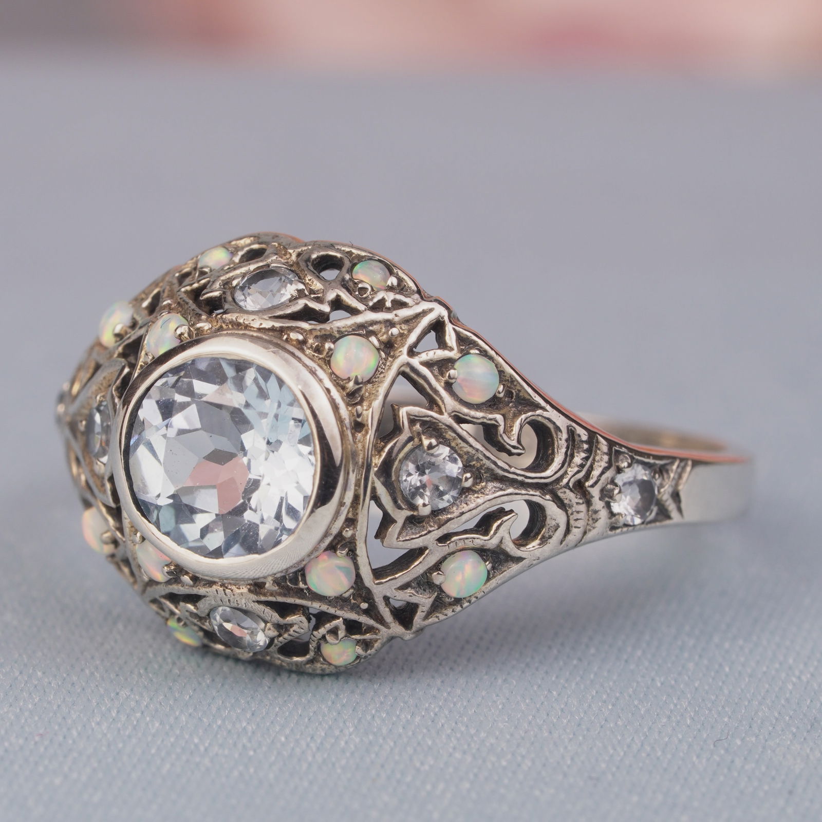 Silver925 Natural Blue Topaz Synthetic Opal White Vintage Filigree Ring: CHARACTERISTICSStatus: In stockOrigin: ThailandMetal: Silver 925Ring Size: US 9Total Gemstones Weight: 2.39 carat. (approx.)Total Gram Weight: 3.24 g. (approx.)*Pictures have been enlarged to show det