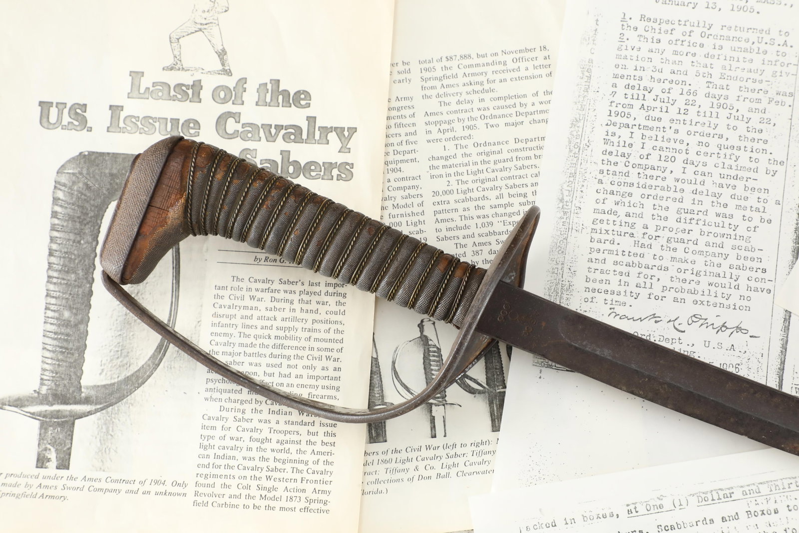 US Army Pre-WW1 Ames Sword Co. Experimental M-1905/06 Cavalry Saber: Fair Condition. Heavy patina and edge chipping to the blade. Moderate patina to the darkened metal “cup” hilt. Heavy tearing to the bottom sharkskin handle covering. Small crack in the exposed