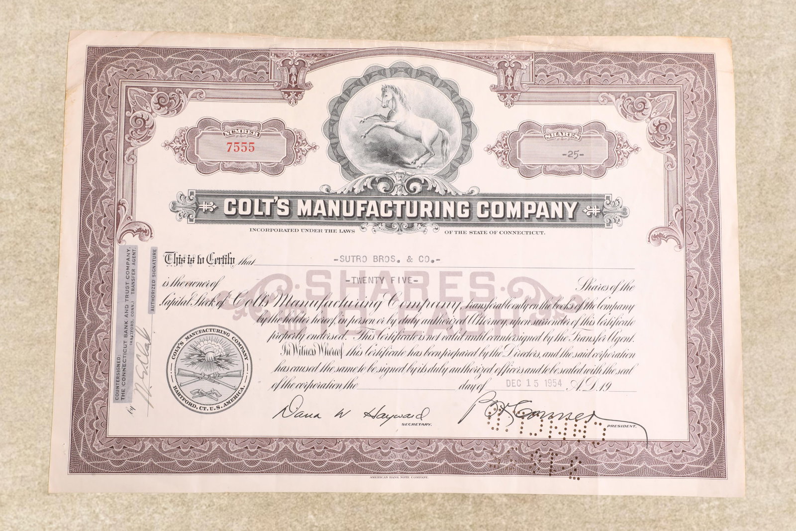 Vintage 1950s Colt's Mfg. Co. Stock Certificate, 25 Shares for Sutro Bros. & Co.: Good Condition. Moderate wrinkling and "browning" along the top edge. Some scattered edge nicking and "browning" to the remainder. Shrink wrapped to a poster board backing. 11 3/4" x 8 1/8". This cert