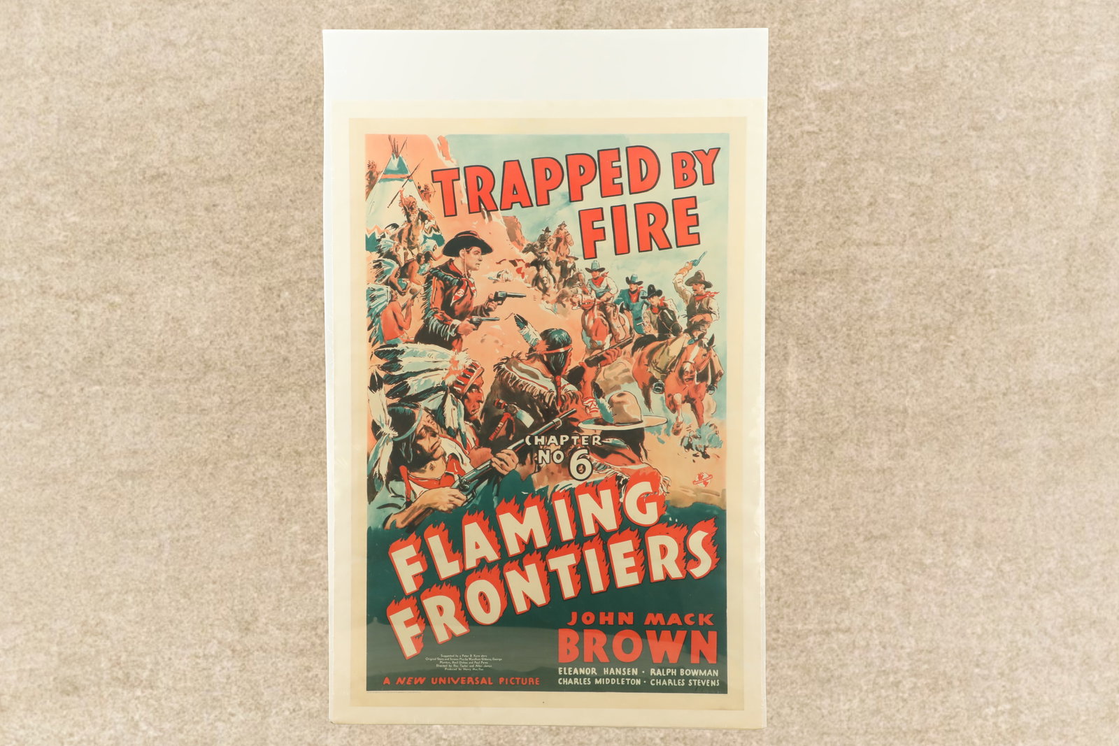 1938 "Flaming Frontiers Chapter No. 6 Trapped By Fire" John Mack Brown Western Movie Poster, 27x41": Very Good Condition. Three horizontal fold lines. A pinhole in each top corner. Some light scattered edge wrinkling and darkening. Linen backed and shrink wrapped to a poster board. 41" x 27 1/4". Fea