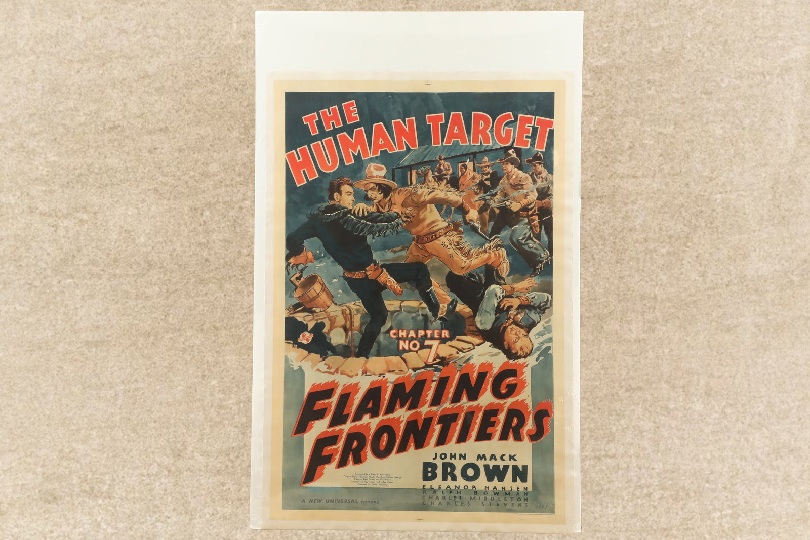 1938 "Flaming Frontiers Chapter No. 7 The Human Target" John Mack Brown Western Movie Poster, 27x41": Very Good Condition. Four horizontal fold lines. A pinhole in each top corner. Some light scattered edge wrinkling. Linen backed and shrink wrapped to a poster board. 41" x 27 3/16". Features a fantas