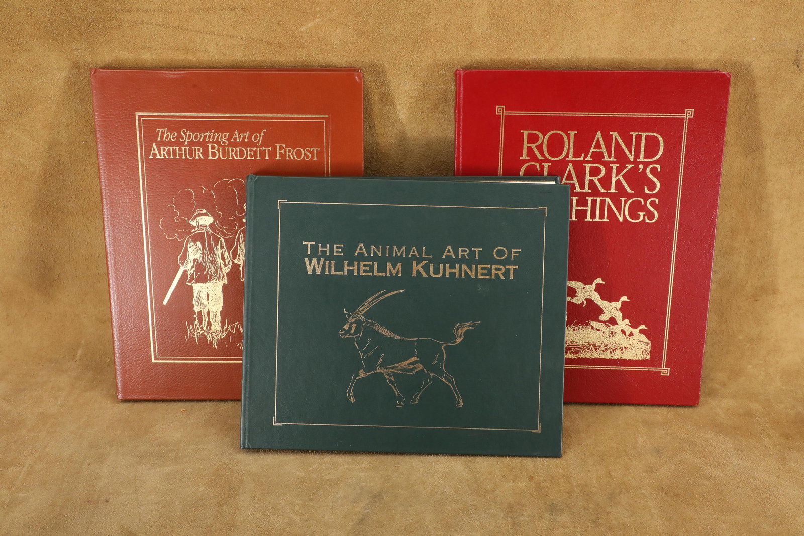 Lot of 3 Leather Bound, Gold Leaf Art Books: Wilhelm Kuhnert, Roland Clark & Arthur Burdett Frost: Very Good Condition. Some light warping to the pages of the Wilhelm Kuhnert book. Some light scattered wear to the spines and covers. All three books were produced for Live Oak Press in 1994 and 1995,