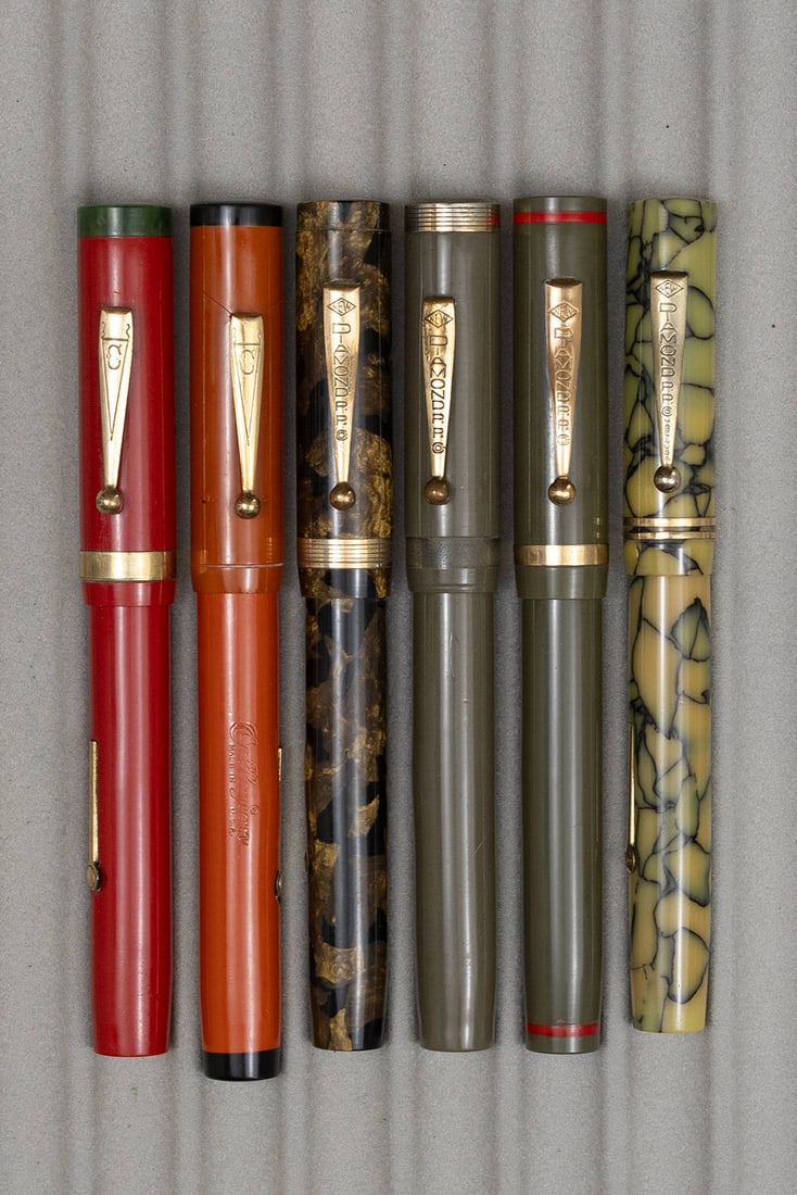 Diamond Point Oversized Flattop Fountain Pen Lot (6): Diamond Point oversized flattop fountain pen lot (6). Diamond Point pens in grey with gold, grey with red, black and pearl and black and bronze along with Collegian (Diamond Point brand) pens in orang