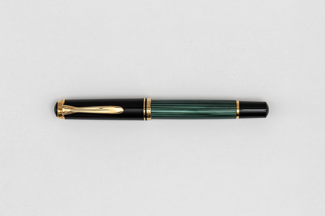 Pelikan M600 Early Model Green Striated Fountain Pen, Italic Nib: Pelikan M600 green striated fountain pen, circa 1989-1997. Early single banded model with replacement Pelikan Italic plated nib. Length 4 7/8” and 5 3/4” posted, filling mechanism piston f