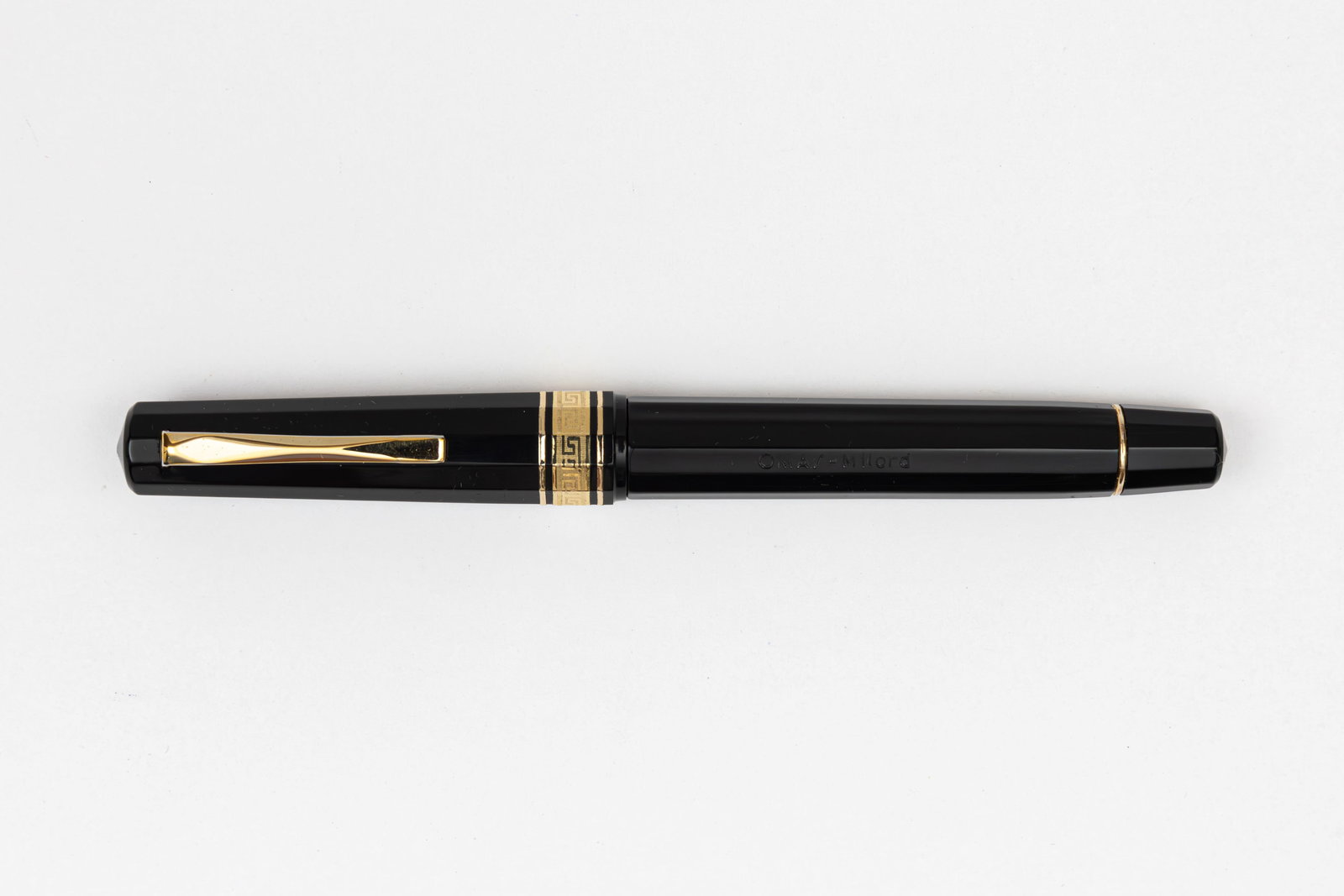 Omas Milord Black GT Fountain Pen: Omas Milord black gold trim fountain pen. Paragon style Milord model with gold trim and greek key cap band with 14K fine nib. Length 5 1/4” and 6 1/4” posted, filling mechanism piston fill
