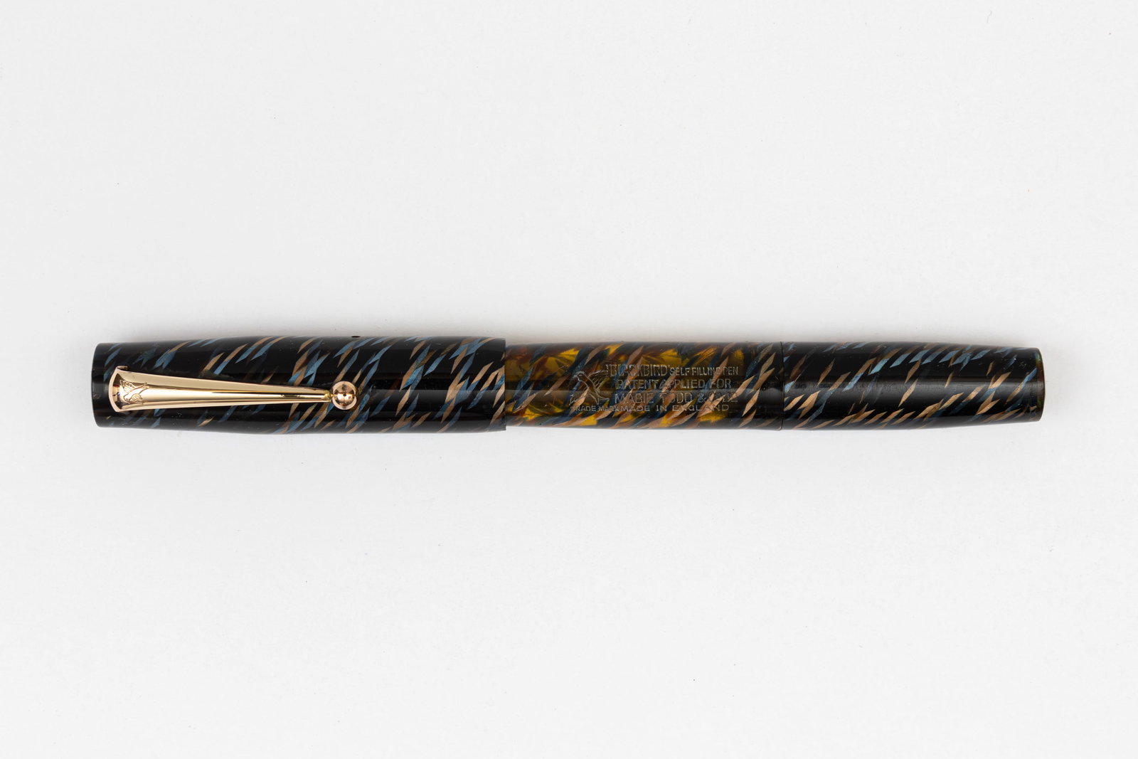 Mabie Todd Swan Blackbird Sacless RT200/82 Fountain Pen: Mabie Todd Swan Sacless Blackbird RT200/82 fountain pen. This Blackbird with gold clip and gold/blue crosshatch colour on black, marketed as the Blackbird Sacless pen with filling system similar to th