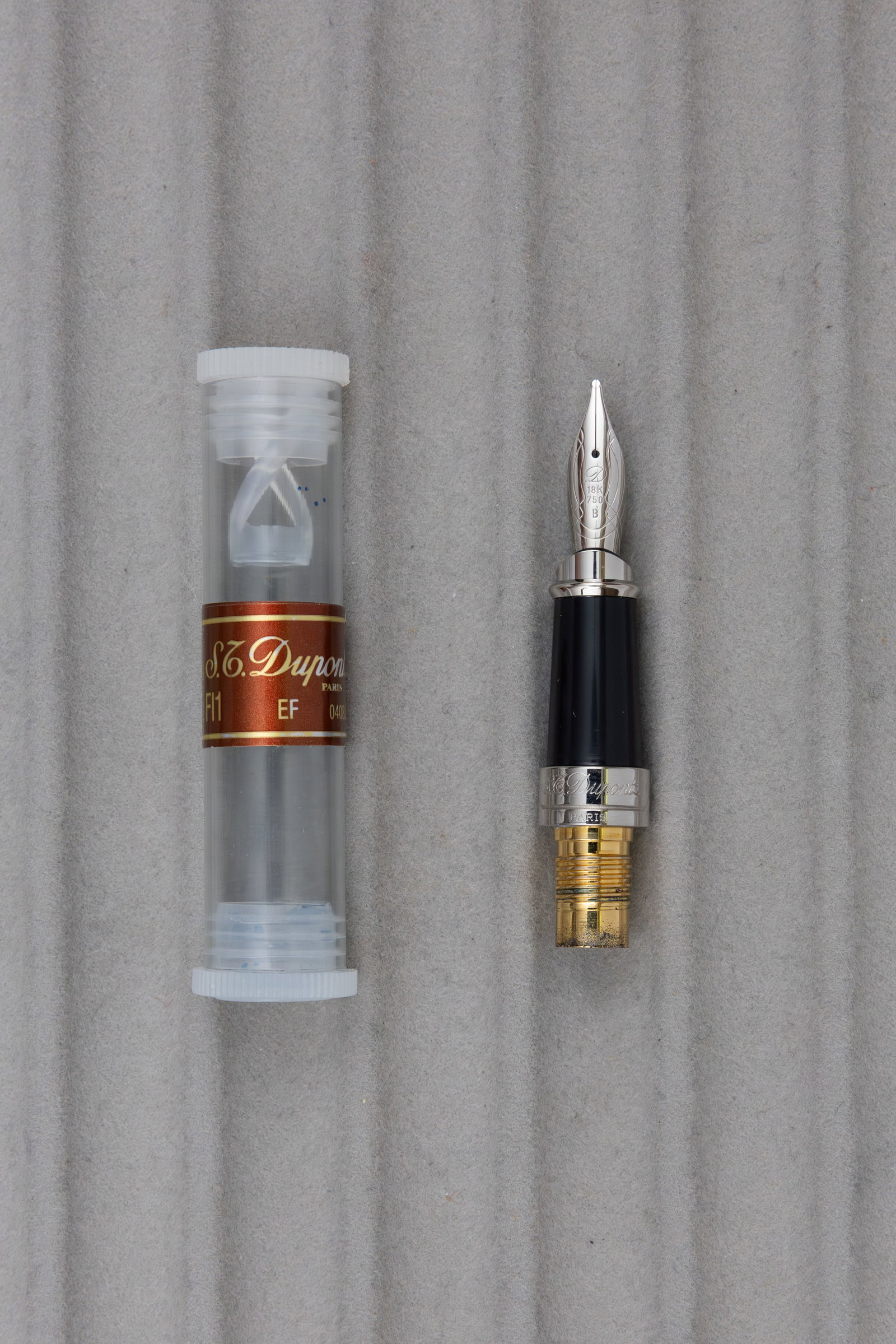 ST Dupont Olympio 18K Broad Fountain Pen Nib Unit: S.T. Dupont Olympio 18K fountain pen nib unit in original tube. Tube marked EF though nib is broad, nib unit for Olympio standard size pen, 18K gold with broad tip, monotone with palladium plate