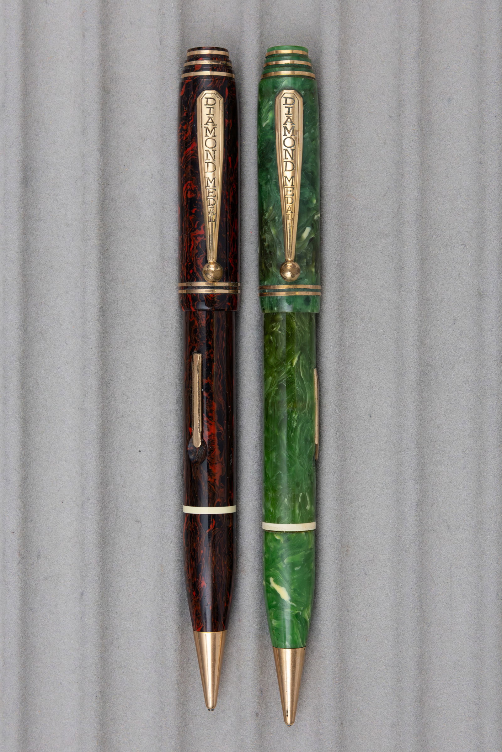 Diamond Medal Art Deco Stepped Cap Fountain Pen Pencil Combos (2): Diamond Medal Art Deco fountain pen, pencil combinations (2). Jade and mahogany marble combinations, both with multiple gold filled bands that run through stepped tops, original Diamond Medal 14K 4