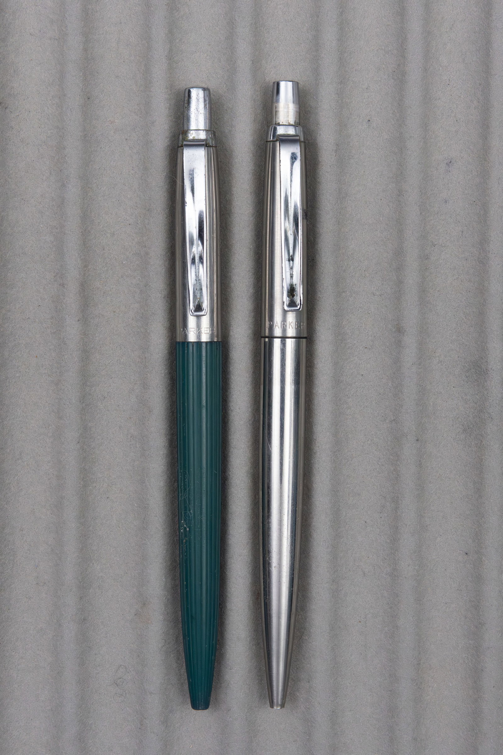 Parker Jotter 1st Year Ballpoint Pens (2): Parker Jotter 1st year ballpoint pens (2). First year Jotter pens in green and stainless. Length 5 1/8 inches, refills dry. Overall good condition, some wear to tops and some marking to green barrel.