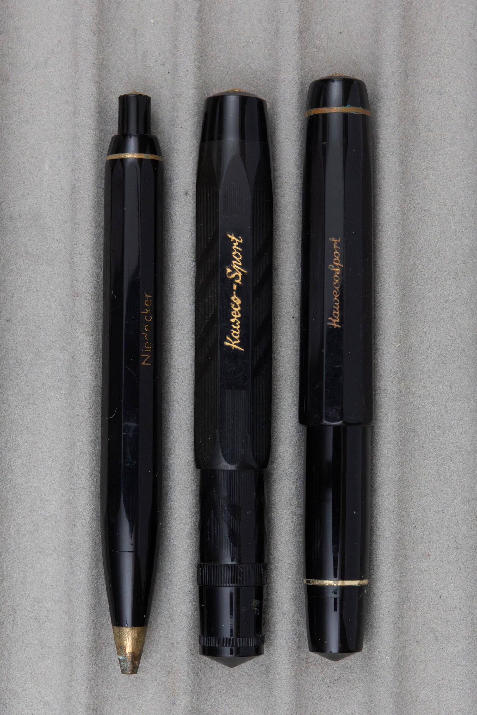 Kaweco Sport Fountain Pen and Set (3), Slip Cases: Kaweco Sport lot (3). Kaweco Sport 712 and 619 set with broad 14K nib along with 112A with extra fine plated nib, both fountain pens piston fill with original slip cases. Overall fair to good conditio