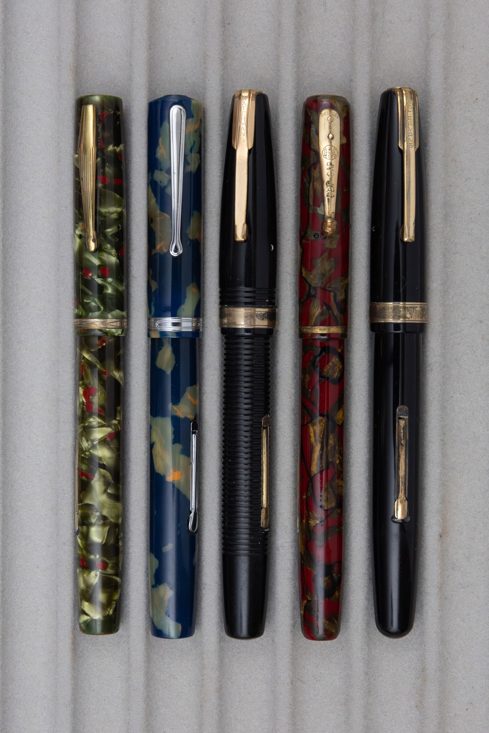 Waterman Ideal 92, 94 and Hundred Year Fountain Pens (5): Waterman 92, 94 and 100 Year fountain pens (5). Waterman 92 fountain pens in green/red and burgundy/gold (cap lip crack), 94 in blue/pearl and Hundred Year pens in black (2). All fountain pens with