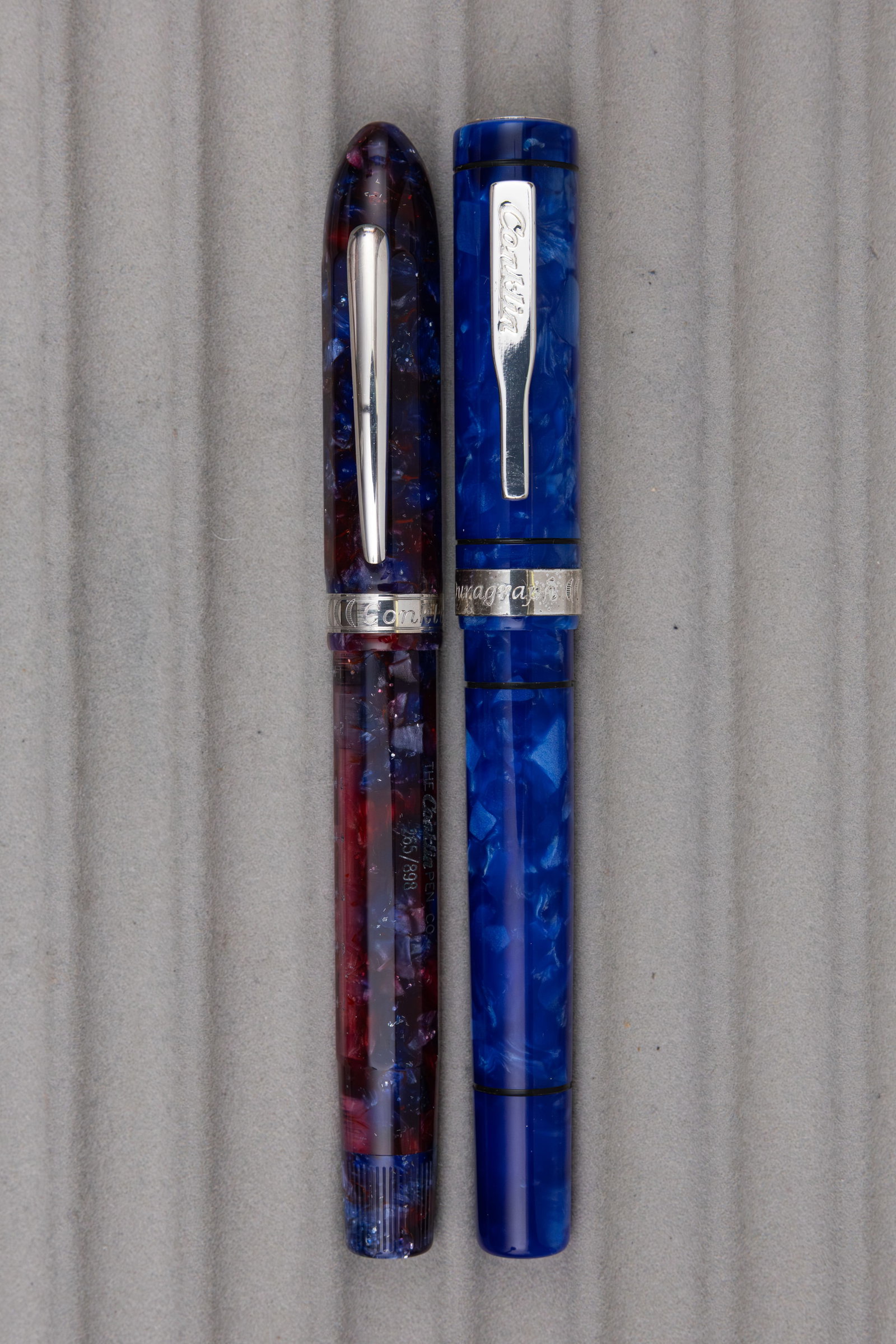 Conklin Duragraph and Nozac Fountain Pens, 14K Nibs: Conklin Duragraph and Nozac fountain pens. Blue marbled Duragraph with 14K medium nib along with limited edition purple/red Nozac (265/898) with 14K fine nib. Length 5 3/4 inches and 7 inches posted, 