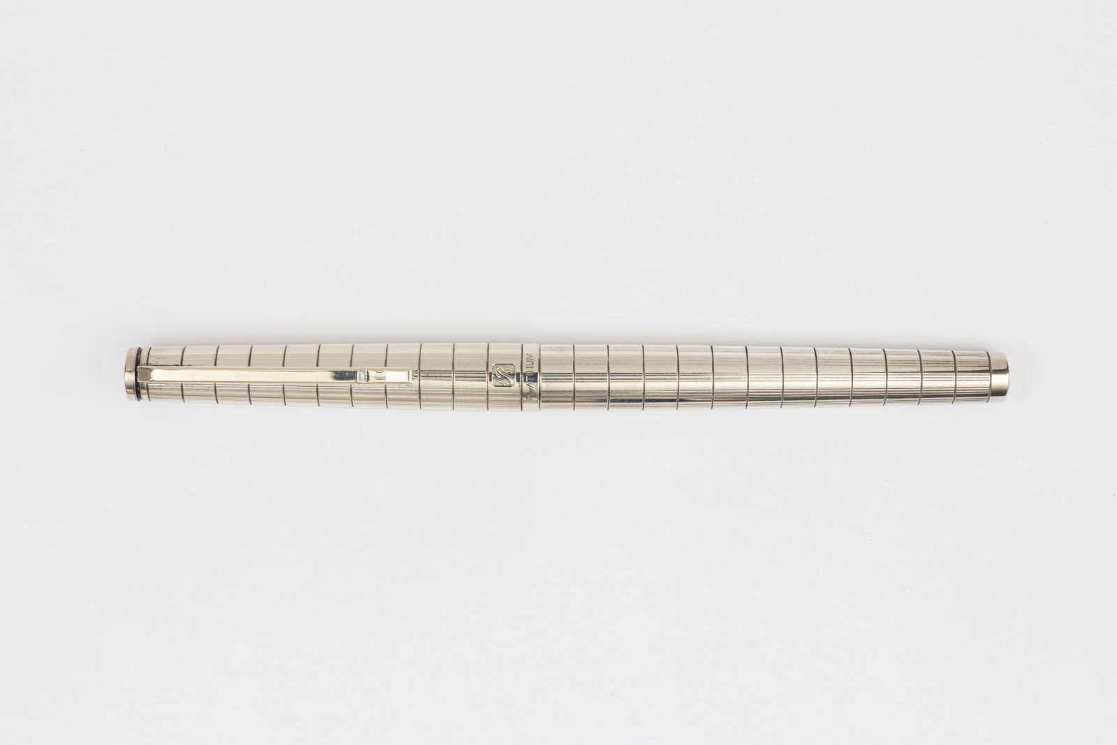 Platinum Riviere Silver Damier Style Fountain Pen: Platinum Riviere silver fountain pen, circa 1970’s. Platinum Riviere in Damier style lined pattern in silver, marked with R on cap but no metal content markings, 18K white gold fine Platinum nib. Le