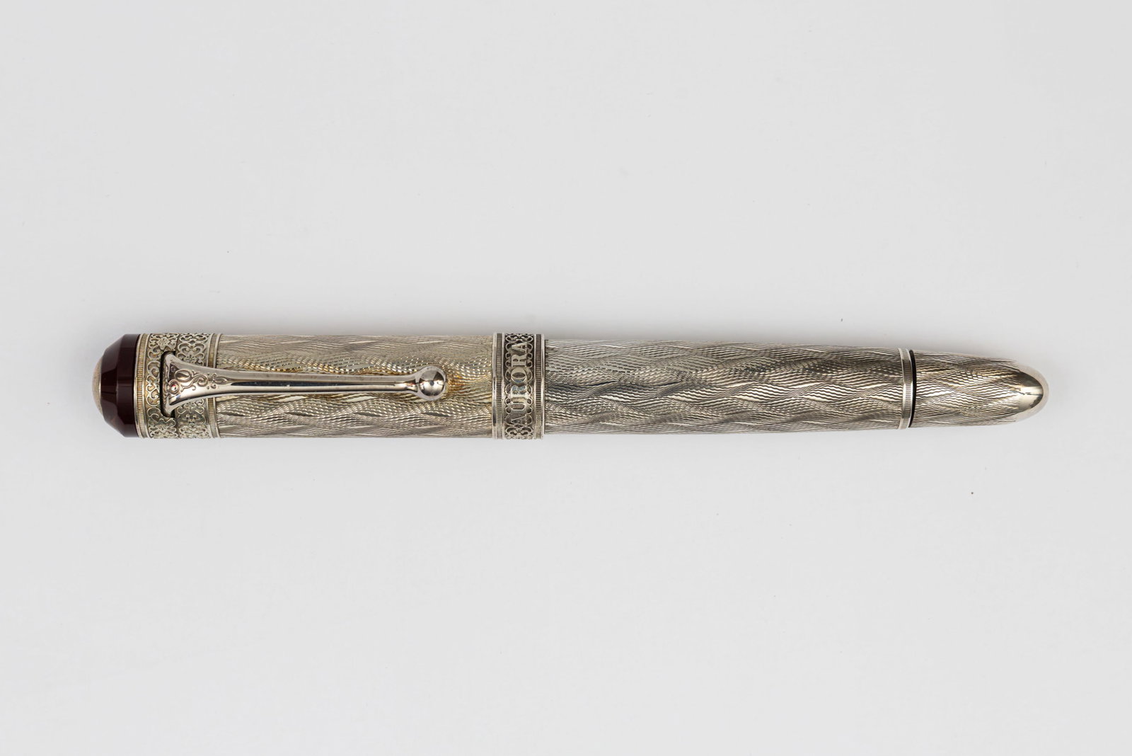 Aurora 80th Anniversary Sterling Silver LE Fountain Pen: Aurora 80th Anniversary limited edition fountain pen in sterling silver guilloche “flame” pattern. Limited to 1,919 pieces (1,562/1,919), this example with Rhodium-treated 18K broad nib. Lengt