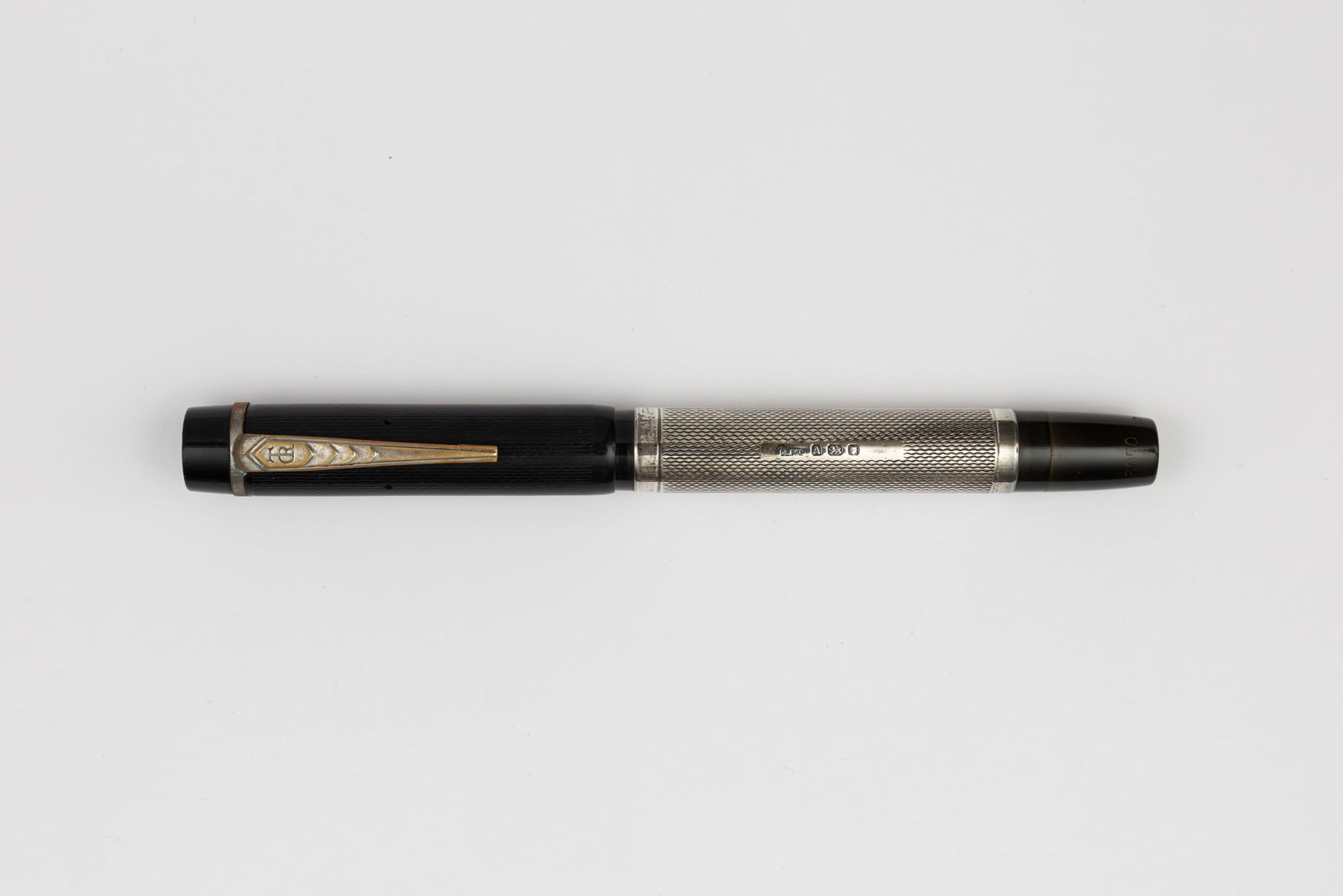 Onoto De La Rue Sterling Silver Barrel Overlay Fountain Pen: Onoto De La Rue sterling silver overlay fountain pen, circa 1930’s. Black chased hard rubber with sterling silver barrel overlay and De La Rue hallmarks with 14K oblique medium flexible nib. Length 