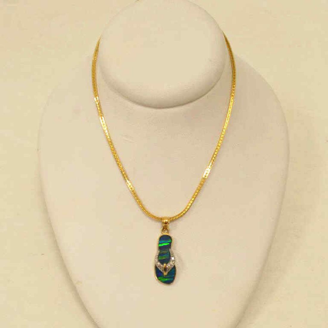 14kt yellow gold sandal necklace: Ladies 14kt yellow gold sandal necklace featuring an inlayed opal sandal pendant accented with round diamonds weighing 0.06ct., hanging from a 16" chain. Weight 6.2 grams