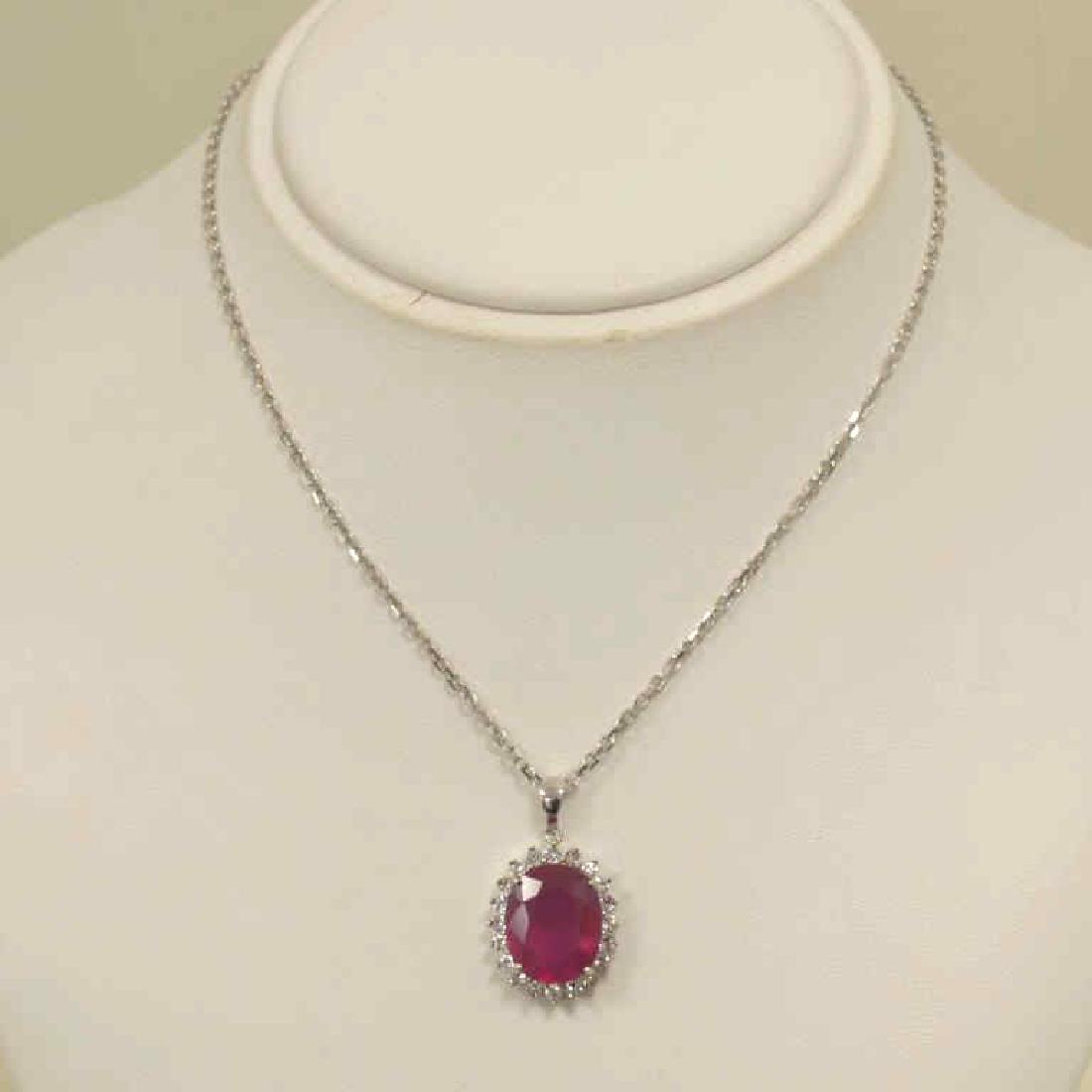 Sterling Sliver Ruby and Sapphire Pendant: Ladies sterling silver ruby and sapphire pendant featuring a prong set oval cut ruby weighing approx. 10.68ct.. Surrounded by a halo of prong set round white sapphires weighing approx. 1.20ct.. Hangin