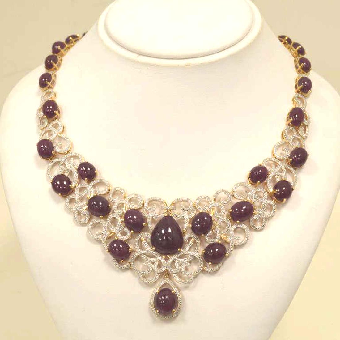 Sterling silver ruby and diamond necklace: Ladies gold toned sterling silver ruby and diamond necklace featuring prong set cabochon cut purplish red rubies weighing approx. 191.82ct.. Accented with a scrolling design of prong set round brillia