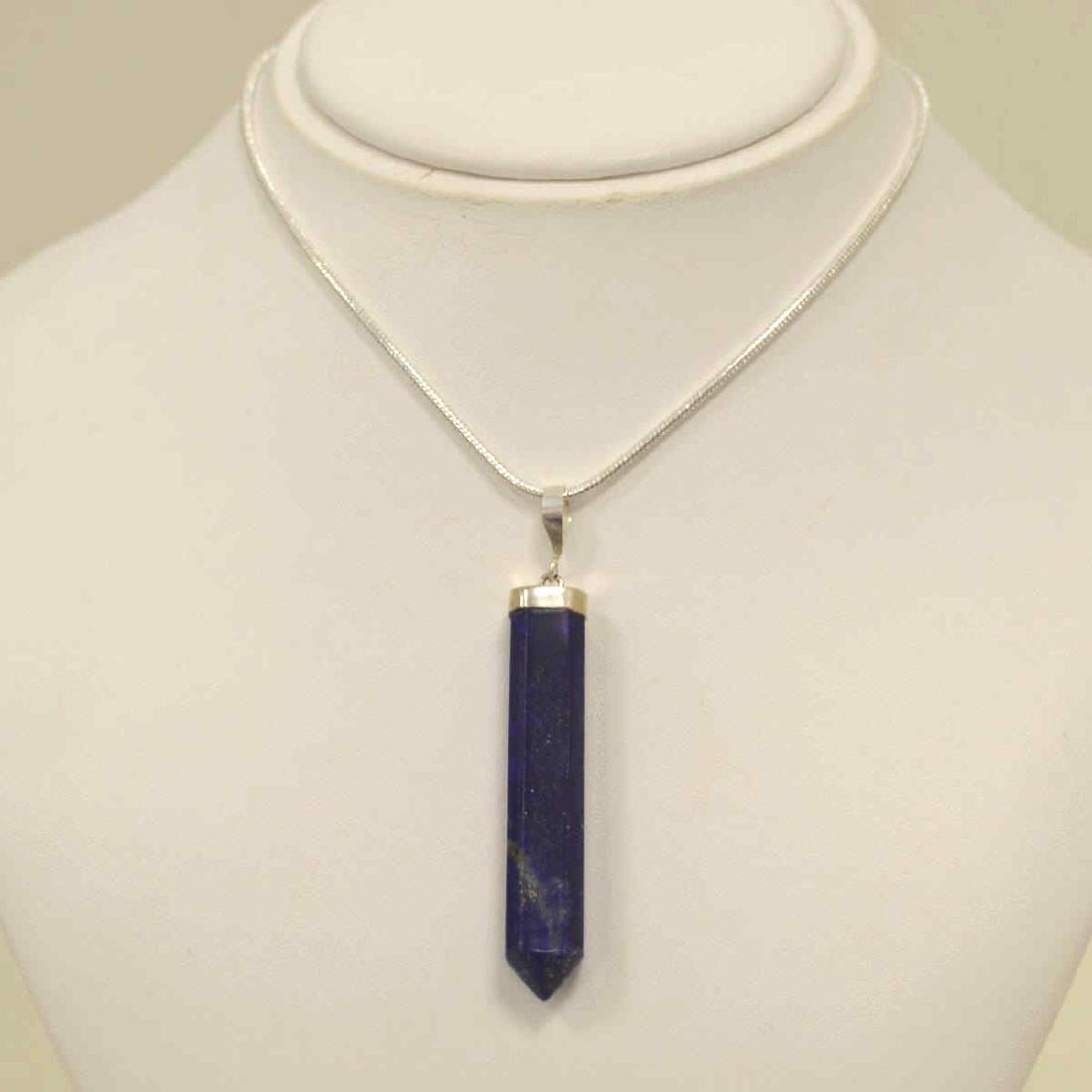 Sterling Silver Lapis Crystal Pendant: Ladies sterling silver lapis crystal pendant featuring a long 6 point faceted lapis pendant weighing approx. 62.10ct.. and displaying streaks of pyrite throughout. Pendant length 2 3/4". Hanging from 