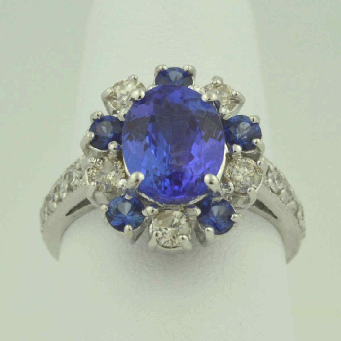 Tanzanite & Diamond Ring: 14kt w/g ring containing a oval tanzanite center stone, medium dark, very slightly grayish violetish blue color, approx 2.43Ct with 5 round blue sapphires, approx .60Ctw alternating with 5 round diamo