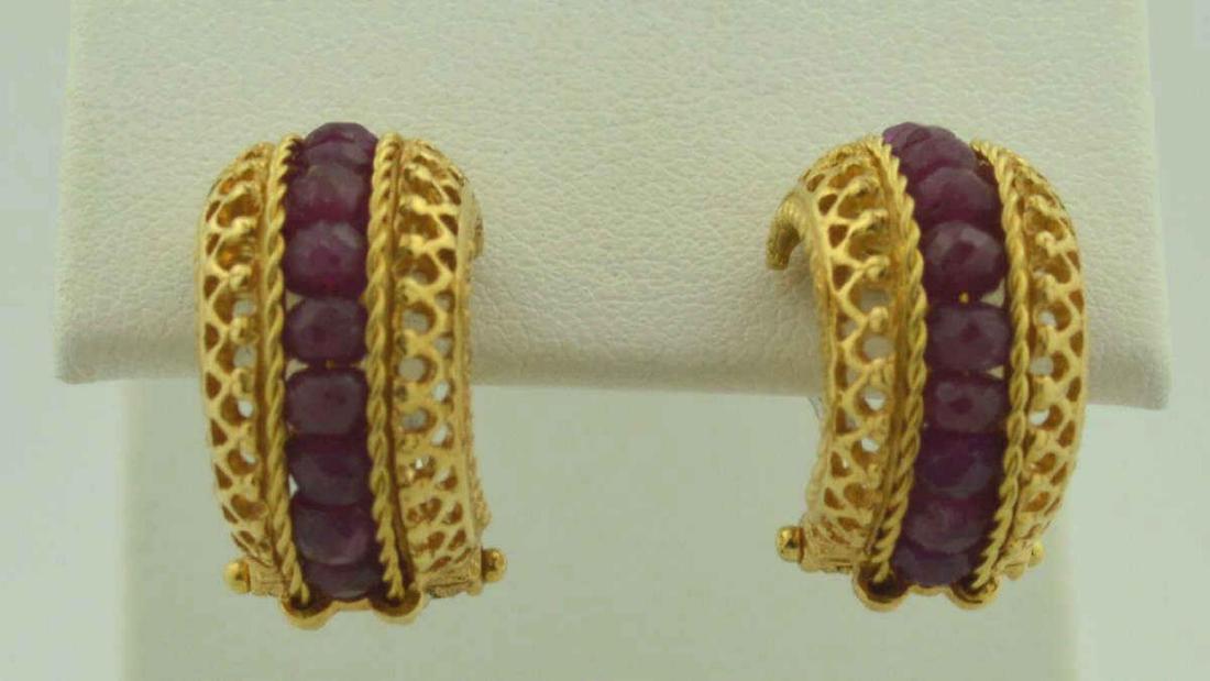18kt yellow gold ruby earrings: 18kt yellow gold earring with a row of faceted rubies in the center and accented with an open scrolling design. Finished with omega backs. Weight 9.3gr.