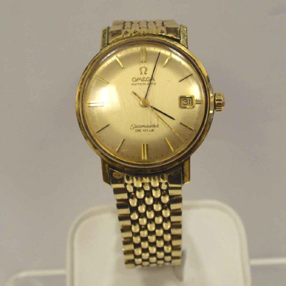 Men's gold toned Omega Seamaster De Ville Watch: Men's gold toned Omega Seamaster De Ville Watch featuring an automatic movement, champagne dial with stick markers and date window, and acrylic crystal. Bracelet length approx. 8". Some scratches on t