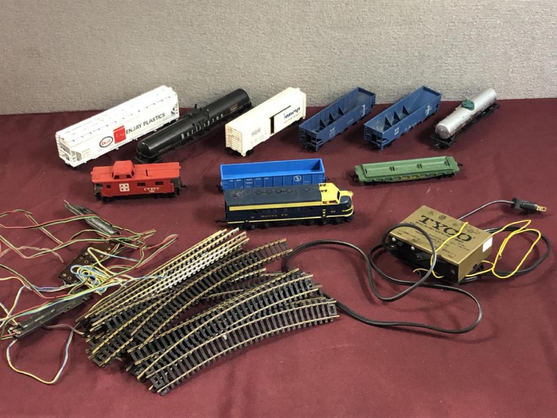 Lot of Toy Train Items, Track Engine Cars Control: Lot of Toy Train Items. HO gauge. One Santa Fe engine, Nine different cars of various types including a A.T.&S.F. caboose car. One TYCO electric transformer model # 899T. Twenty pieces of track (vario