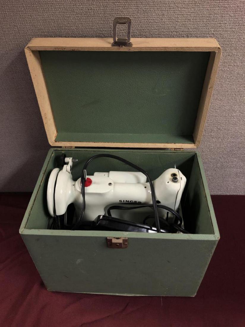 Singer Portable Electric Sewing Machine in Case: Singer Vintage Collectible Portable Electric Sewing Machine in Carry Case. 221K Featherweight. It has the original foot switch & case. It has an external electric belt driven motor. The belt is better