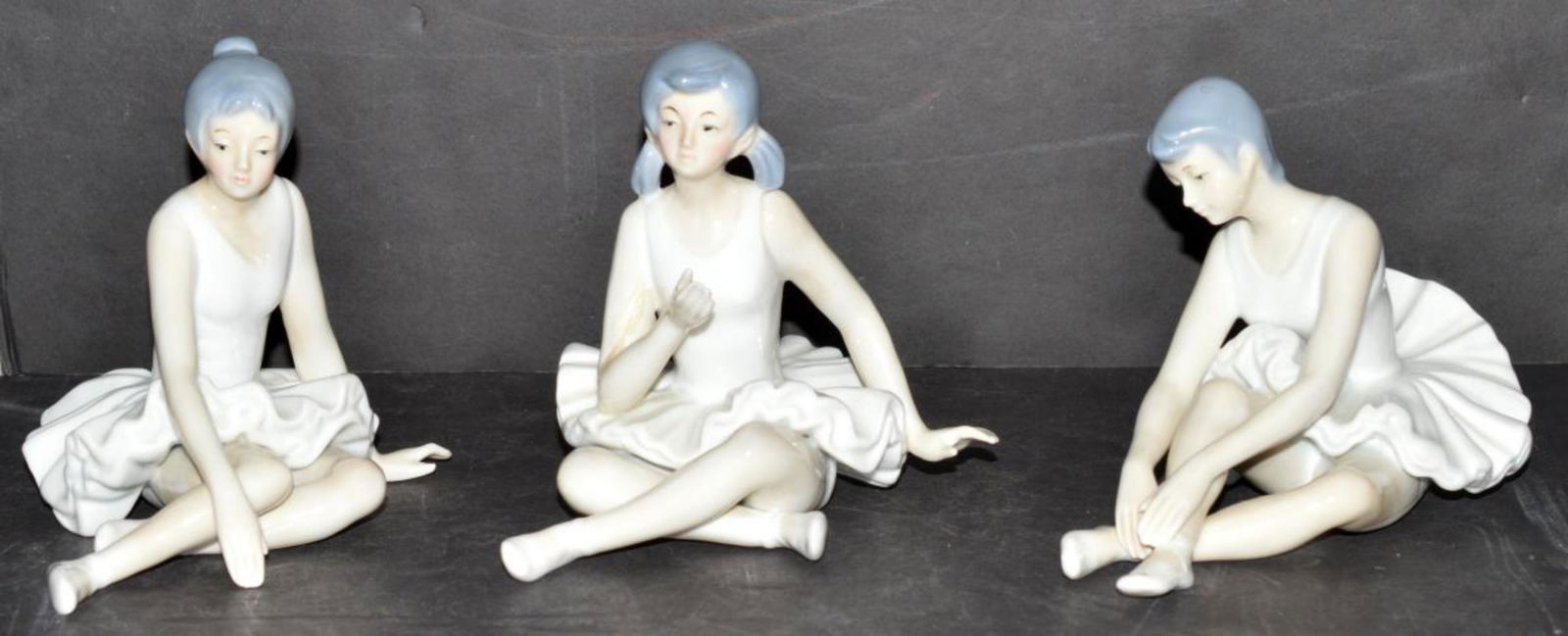 Lot of 3 Porcelain Seated Ballerina Figurines: Lot of 3 Ceramic Porcelain Seated Ballerina Figurines in the manner or styling of Lladro & Nao. All three are unmarked, glazed finish. They are 5" - 5.75" tall. One has a broken and repaired arm.