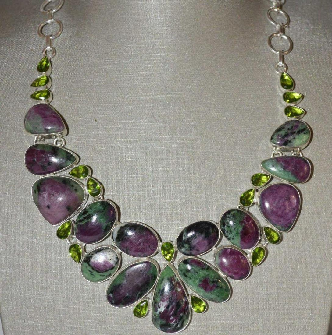 Ladies sterling silver ruby zoisite necklace: Ladies sterling silver ruby zoisite necklace featuring various shape bezel set polished ruby zoisite weighting approx 222cttw. Accented with bezel set pear shape peridot. Length 18". Weight 79.4 grams