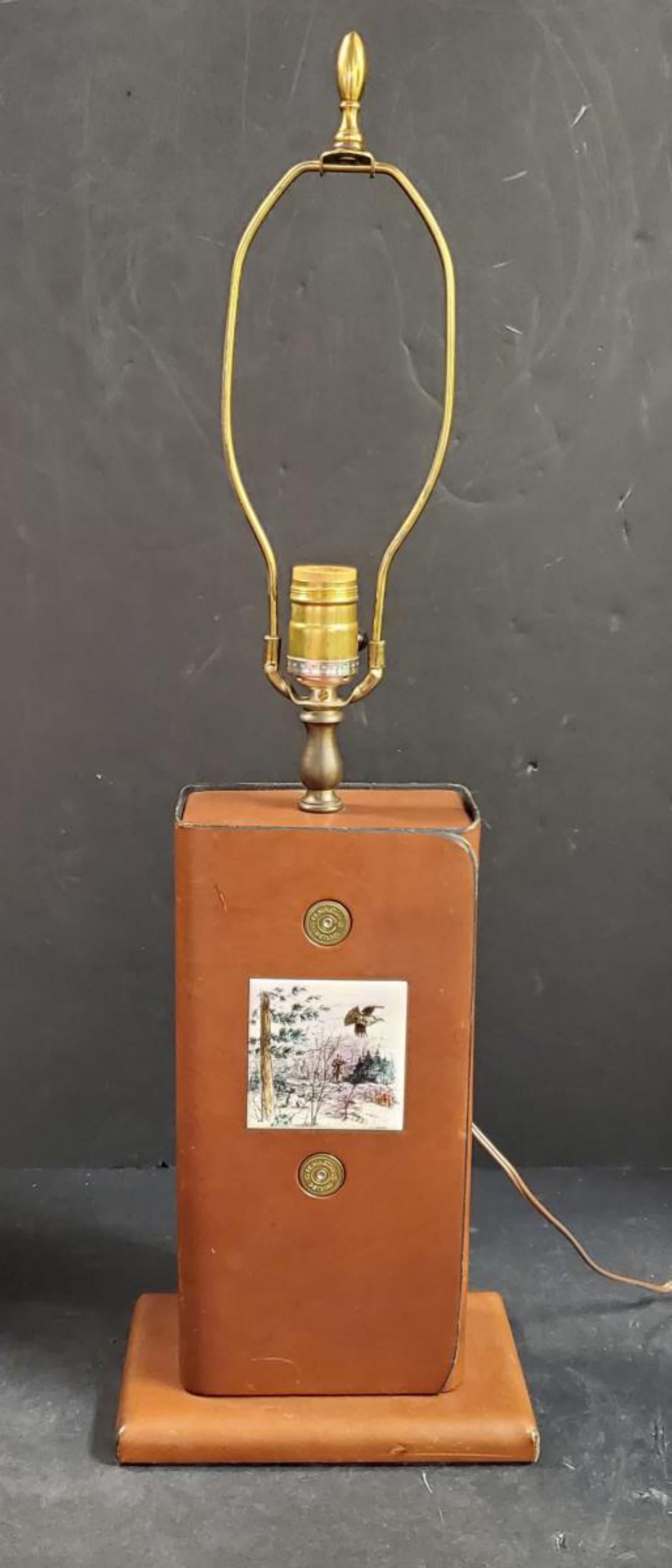 Rustic Leather Wrapped Electric with Grouse Tile: Rustic Leather Wrapped Electric Lamp with Grouse Tile Embellishment or Inlay. This brown leather lamp has black piping & antique brass tone single socket lamp riser. It has Remington shotgun shell bra
