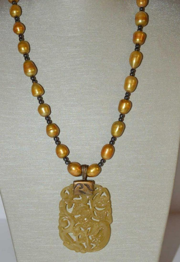 Baroque pearl bead necklace: Dyed baroque pearl bead necklace featuring dyed golden color baroque pearls measuring approx. 9mm and separated by shiny black beads. Finished with a carved resin pendant. Length 20".