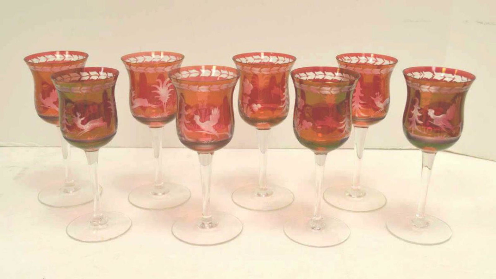 Lot of 8 Cranberry Color Small Wine Glasses: 8 cranberry color small wine glasses with clear glass pattern of deer and various fowl. Glass has been flashed to give the cranberry color.