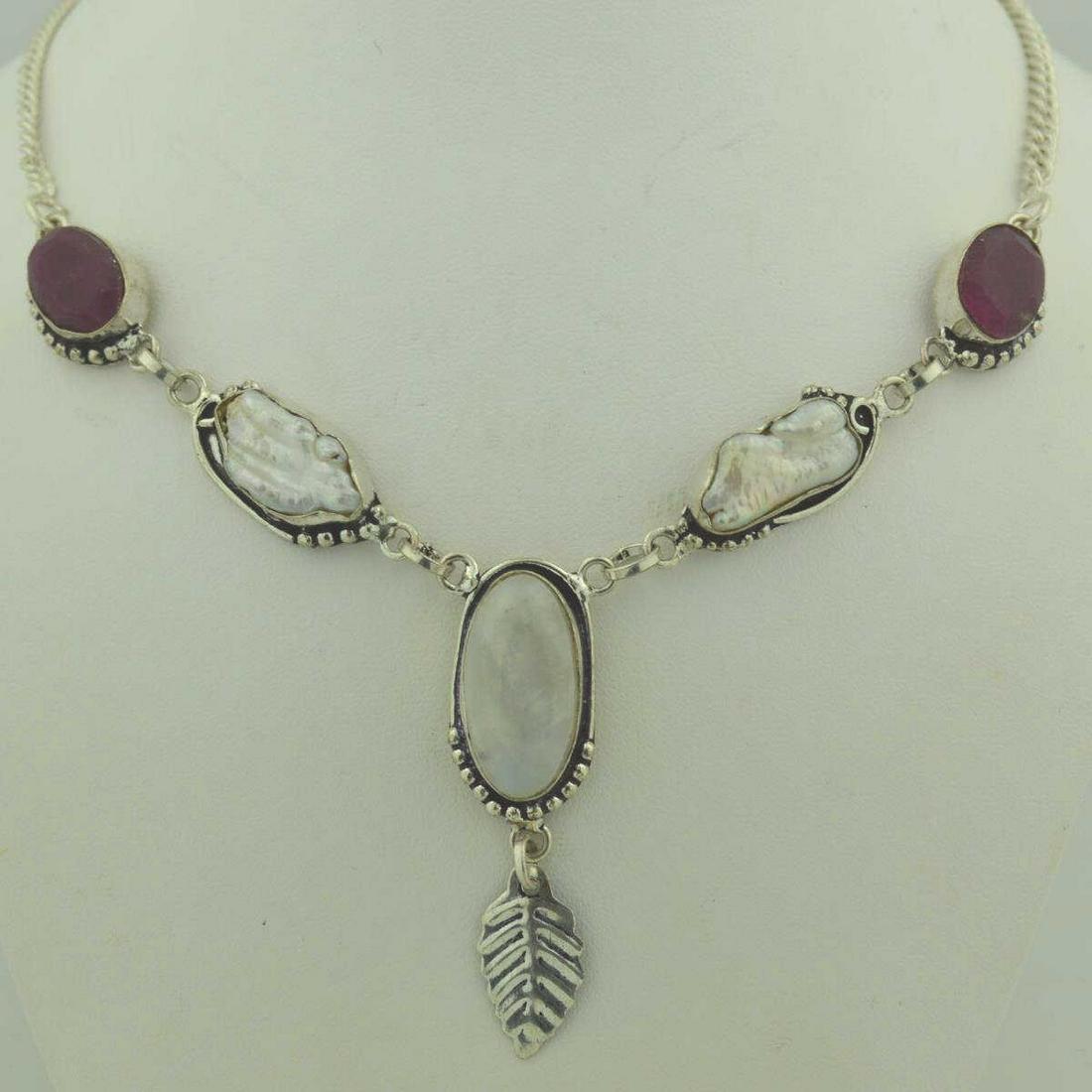sterling ruby, pearl, and moonstone necklace: Ladies sterling silver ruby, pearl, and moonstone necklace featuring two bezel set opaque ruby, two bezel set freshwater baroque pearls and one bezel set cabochon moonstone. Accented with leaf and bea