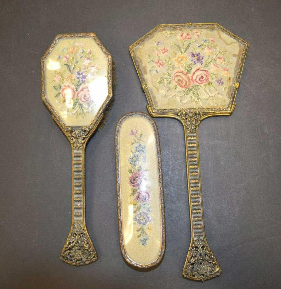 Vintage Vanity Set, Mirror & Brushes: Vintage vanity set with needlepoint tapestry backs depicting flowers. Lot includes a mirror and 2 brushes. The mirror in missing the plastic cover and has some deterioration.