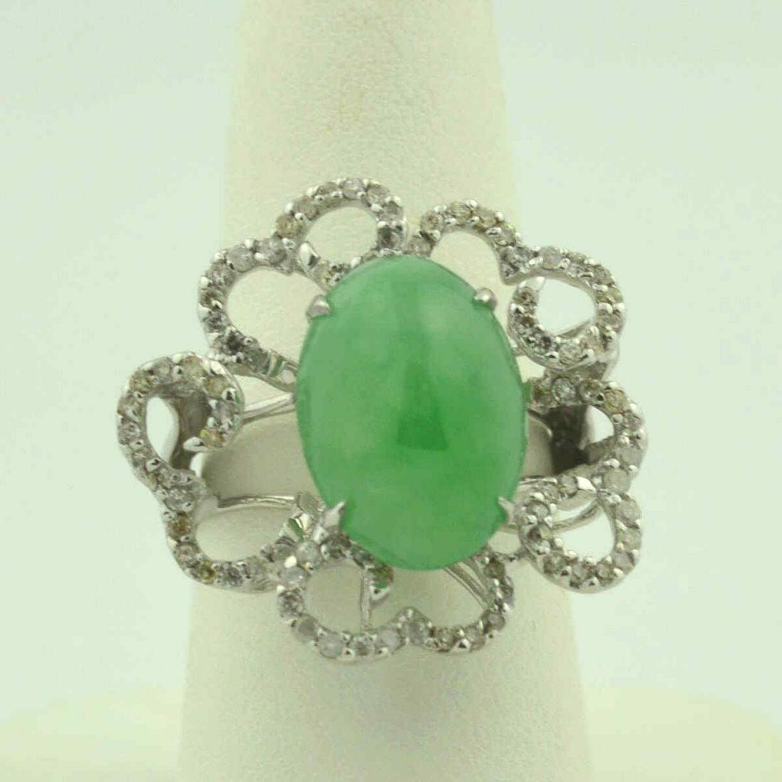 14kt white gold jadeite and diamond ring: Ladies 14kt white gold jadeite and diamond fashion ring featuring a prong set oval cabochon cut jadeite weighing approx. 8.66ct.. Accented with a flowing frame of prong set round brilliant cut diamond