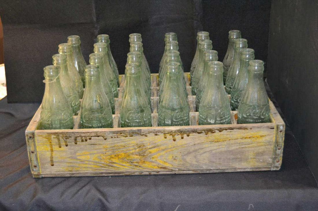 Case of Vintage Coca-Cola Bottles in Wood Box: Vintage case of glass Coke or Coca-Cola Bottles. 24 glass 6 & 6.5 oz bottles typically found in he old refrigerated vending machines, all in yellow wooden individually slotted box marked Coca-Cola on