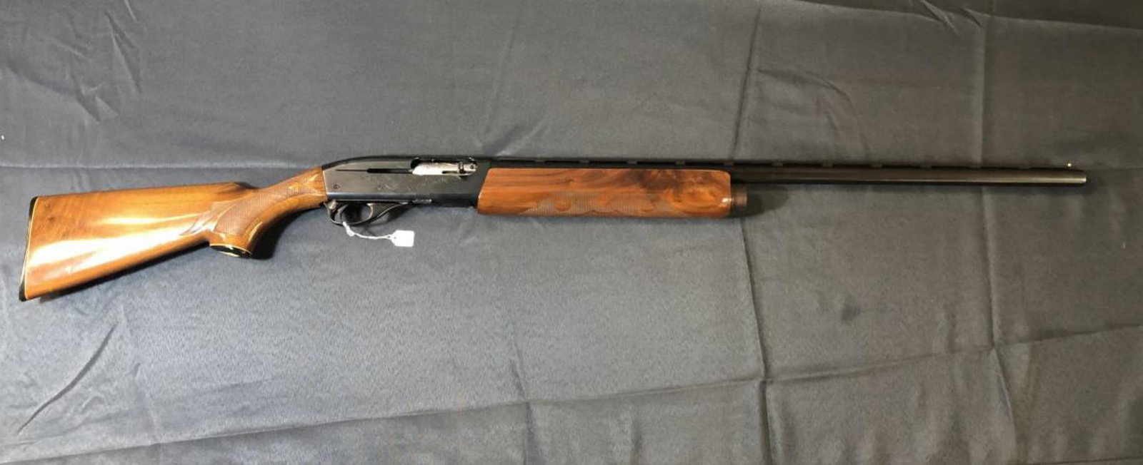 Remington 1100 Vented Rib Semi Auto 12 Gauge: Remington 12 Gauge Model 1100 Semi-Automatic Shotgun. Blue metal with high gloss checkered wood stocks with iconic white diamond inlay. 28" vented rib barrel with bead sight for 2 3/4" shells. Engrave