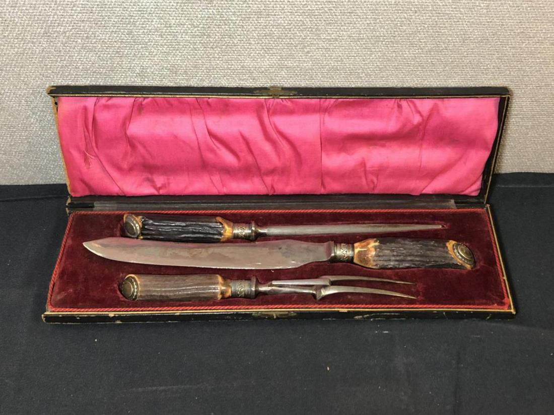 Vintage Thomas Wilson Knife & Fork Carving Set: Carving Set. Comes with knife, Fork, & Steel. Lined in satin and felt Black box. Their is some wear on th outside of the box. Carved wood handles. Trade Mark Thomas Wilson Cutter & Silversmith Sheffie