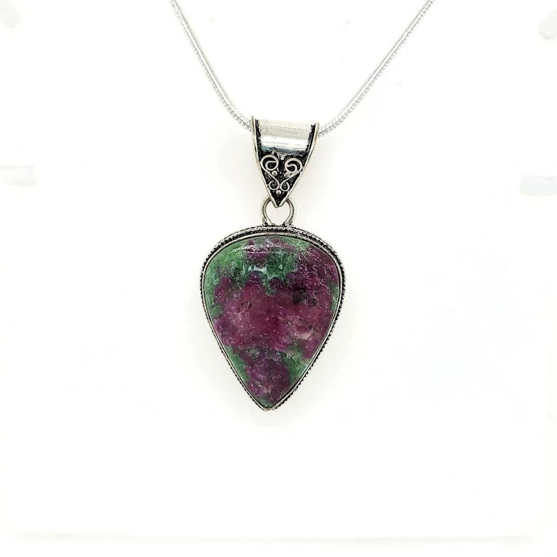 Sterling Silver Ruby Zoisite Pendant: Ladies sterling silver ruby zoisite pendant featuring a bezel set pear shaped cabochon cut ruby zoisite weighing approx. 49.50ct. and accented with a scrolling design frame. Hanging from a 20" snake c