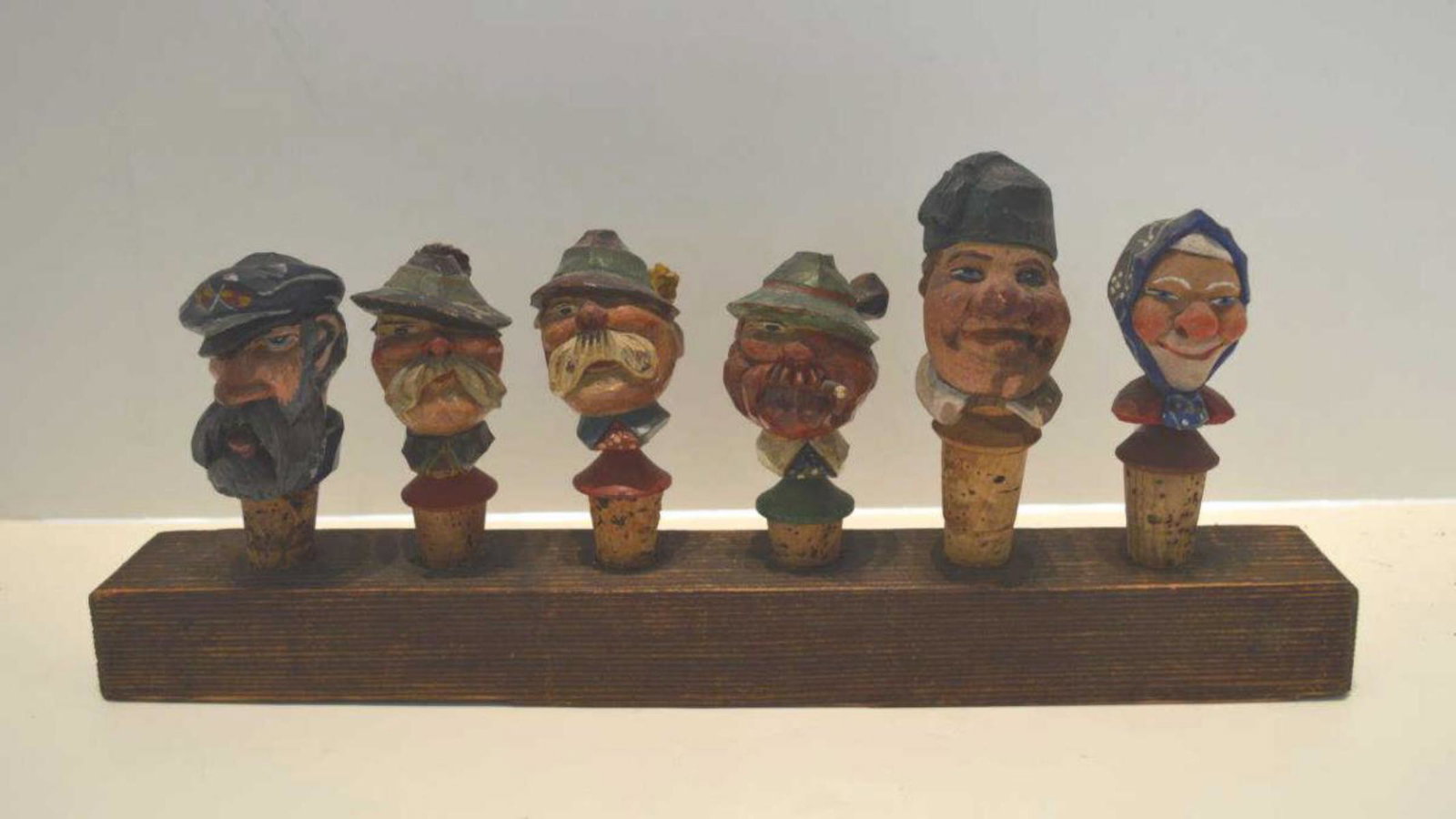 Six Folk Art Wood Carved Wine Stoppers w/Stand: 6 carved wooden wine stoppers with slotted stand. Various bust carving of men and a woman.