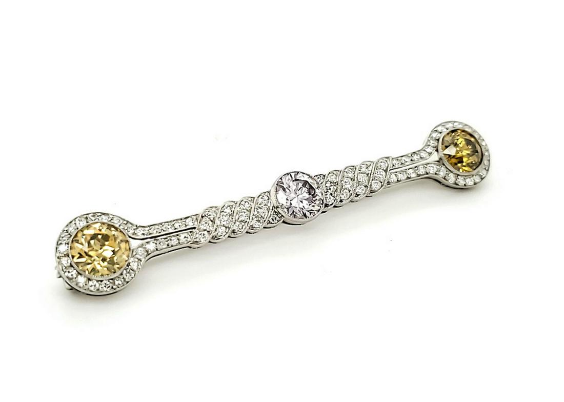 Platinum fancy color diamond bar pin: Ladies platinum diamond bar pin containing 3 bezel set round transitional cut fancy color diamonds. One medium light slightly brownish orangy yellow, Clarity I1, weighing approx. 1.19ct., one very lig