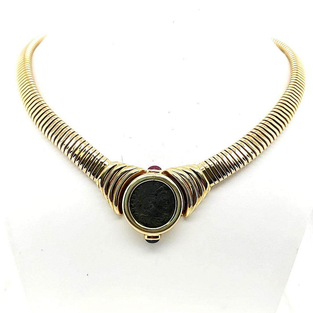 14kt yellow gold ancient coin collar necklace: Ladies 14kt yellow gold ancient coin collar necklace featuring a flexible ridged collar accented with a bezel set ancient copper coin. Detailed with oval cabochon cut ruby and sapphire. Length approx.