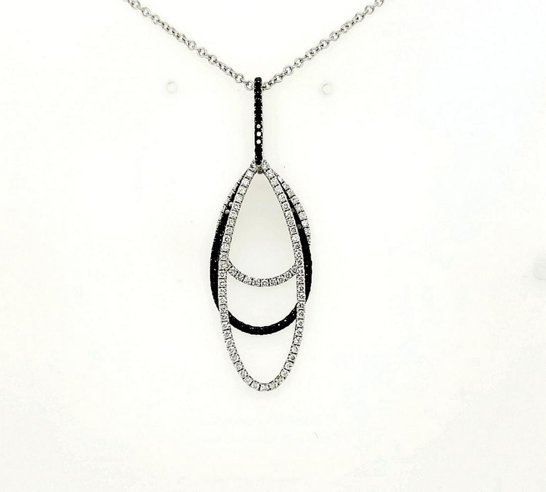 18kt white gold black and white diamond pendant: Ladies 18kt white gold black and white diamond oval pendant featuring moving ovals of prong set round black and white diamond. Black diamonds weighing 0.46ct and white diamonds weighing approx. 0.75ct