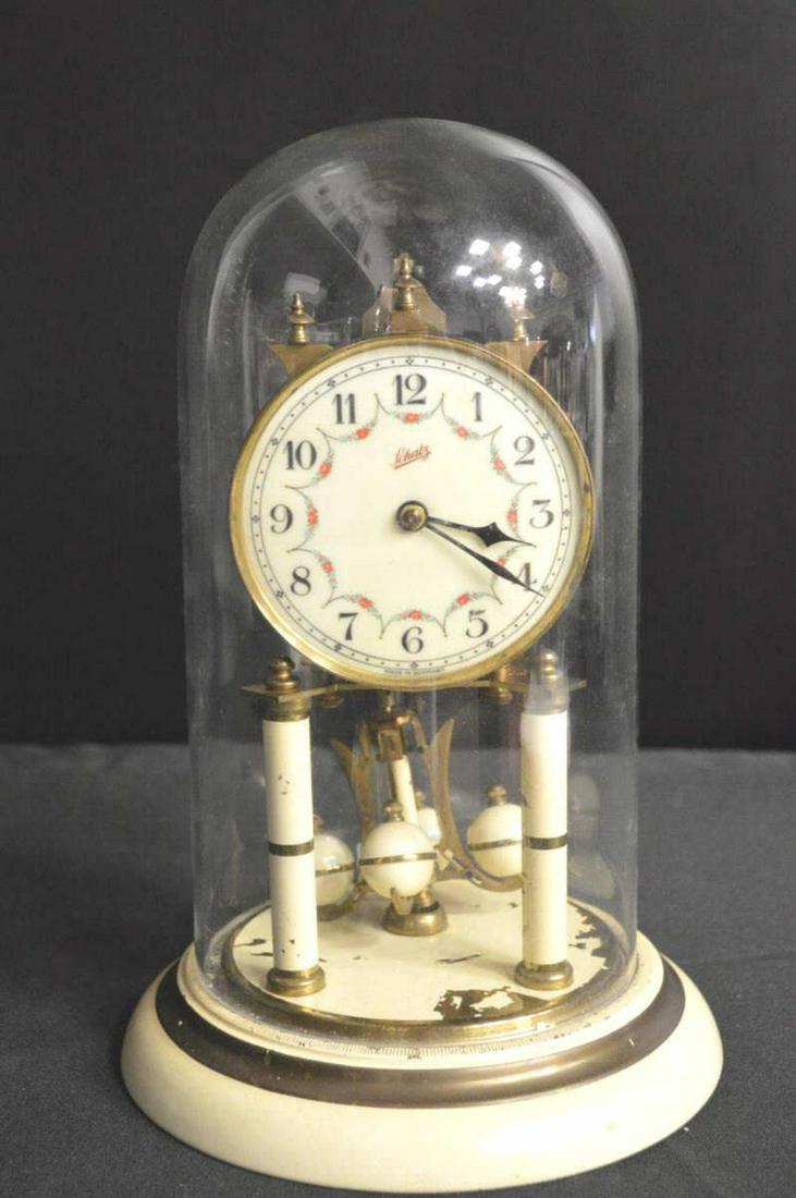 Shatz German made Model 49 Anniversary Clock: Shatz German made Model 49 Anniversary Clock with Glass Globe. Brass & ivory colored base & uprights & pendulum. Arabic numerals. Marked made in Germany on the bottom. Movement is marked 49. With key.