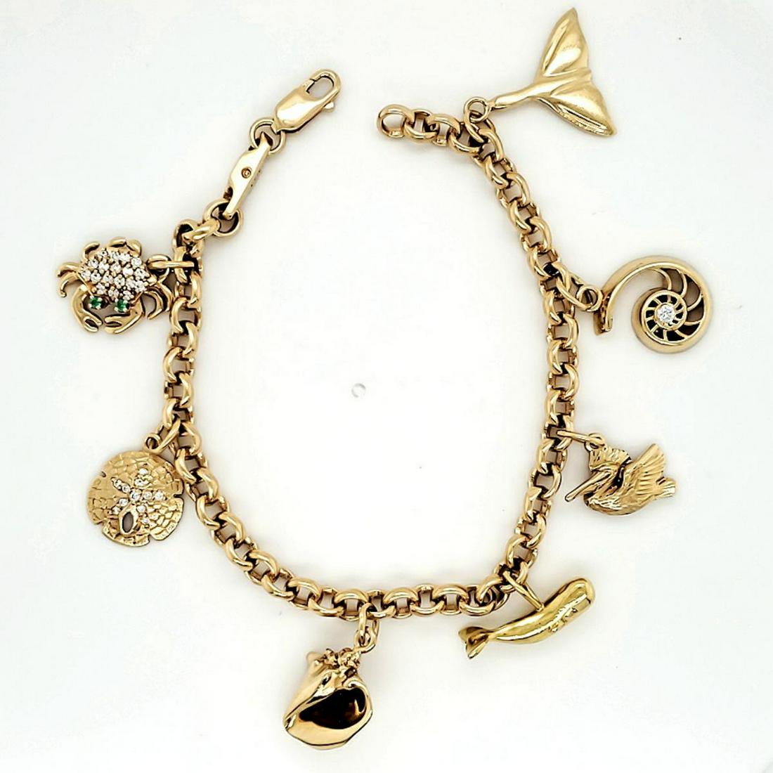 14kt yellow gold nautical theme charm bracelet: Ladies 14kt yellow gold nautical theme charm bracelet featuring a rolo link bracelet with a crab, sand dollar, conch, whale, pelican, nautilus shell and whale tale charms. Length 7.5". Weight 27.3 gra